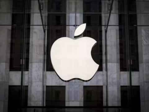 من iPhoneIslam.com، يظهر شعار شركة Apple أمام مبنى زجاجي، يرمز إلى هيمنة شركة Apple ونظام الدفع الخاص بها.