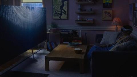 من iPhoneIslam.com، رجل يجلس أمام التلفاز في غرفة المعيشة.