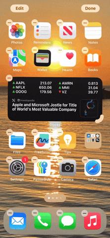 من iPhoneIslam.com، تعرض شاشة iPhone الرئيسية أيقونات التطبيقات المختلفة ونظام التشغيل iOS. تظهر صورة الخلفية غروب الشمس فوق الماء. تحتوي بعض التطبيقات على علامة ناقص صغيرة، تشير إلى إمكانية إزالتها أو إعادة تنظيمها. في iOS 18، يمكنك تغيير حجم الويدجت لتخصيص أفضل.