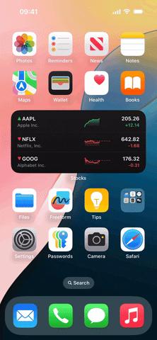 من iPhoneIslam.com، تعرض شاشة الهاتف الذكي التي تعمل بنظام iOS 18 أيقونات تطبيقات متنوعة بما في ذلك الصور والتذكيرات والملاحظات والخرائط. تعرض أداة الأسهم أسعار واتجاهات أسهم Apple وNetflix وAlphabet. الخلفية متدرجة. خيارات تثبيت الويدجت تغيير حجم الويدجت متاحة للتخصيص.
