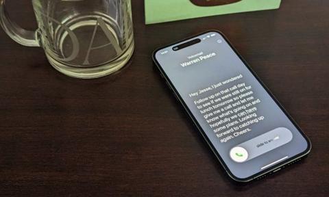 من iPhoneIslam.com، يجلس هاتف iPhone XS على طاولة بجوار كوب من الماء، ويضم 10 ميزات جديدة تأتي مع نظام التشغيل iOS 17.