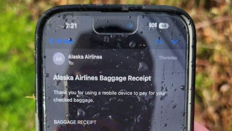 من iPhoneIslam.com، يعرض هاتف أحد الأشخاص إيصال الأمتعة الخاص بشركة طيران ألاسكا.